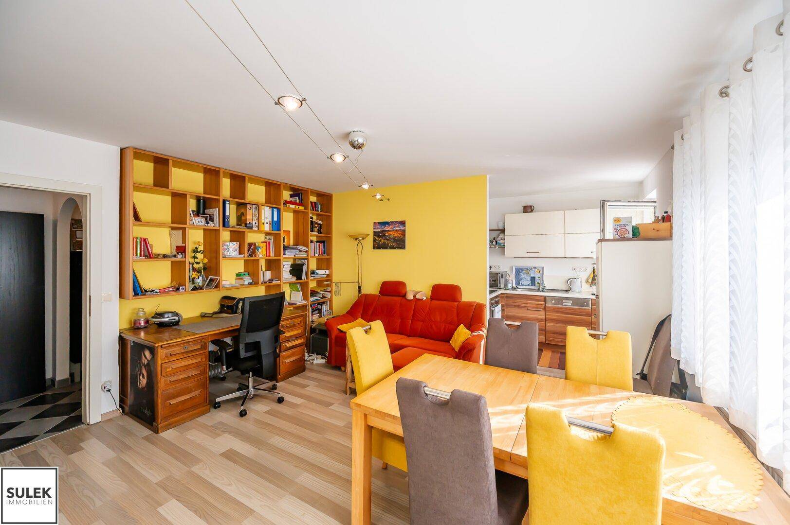 Kombinierter Wohn- und Essbereich mit offener Küche, Laminatboden und integriertem Büro.
