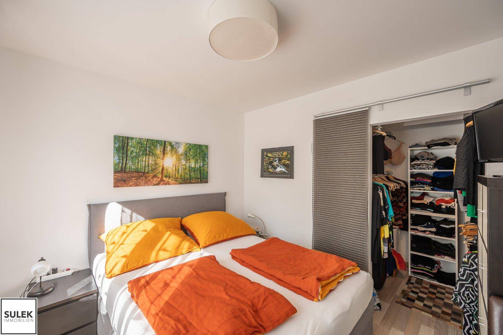 Schlafzimmer mit Doppelbett, hellem Laminatboden und praktischem Einbauschrank.