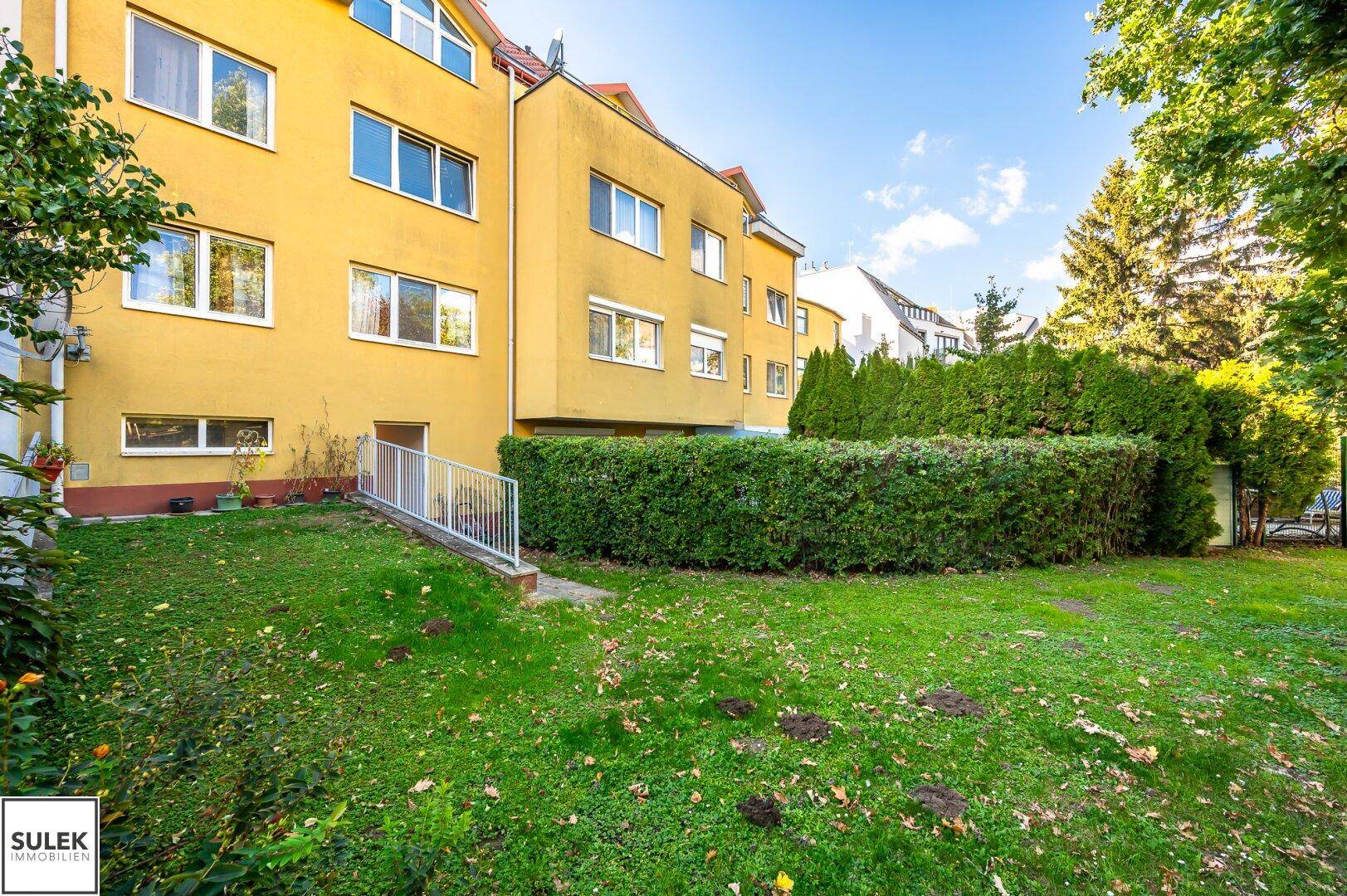 Großer Gemeinschaftsgarten mit Rasen und Blick auf die Gebäudefassade.