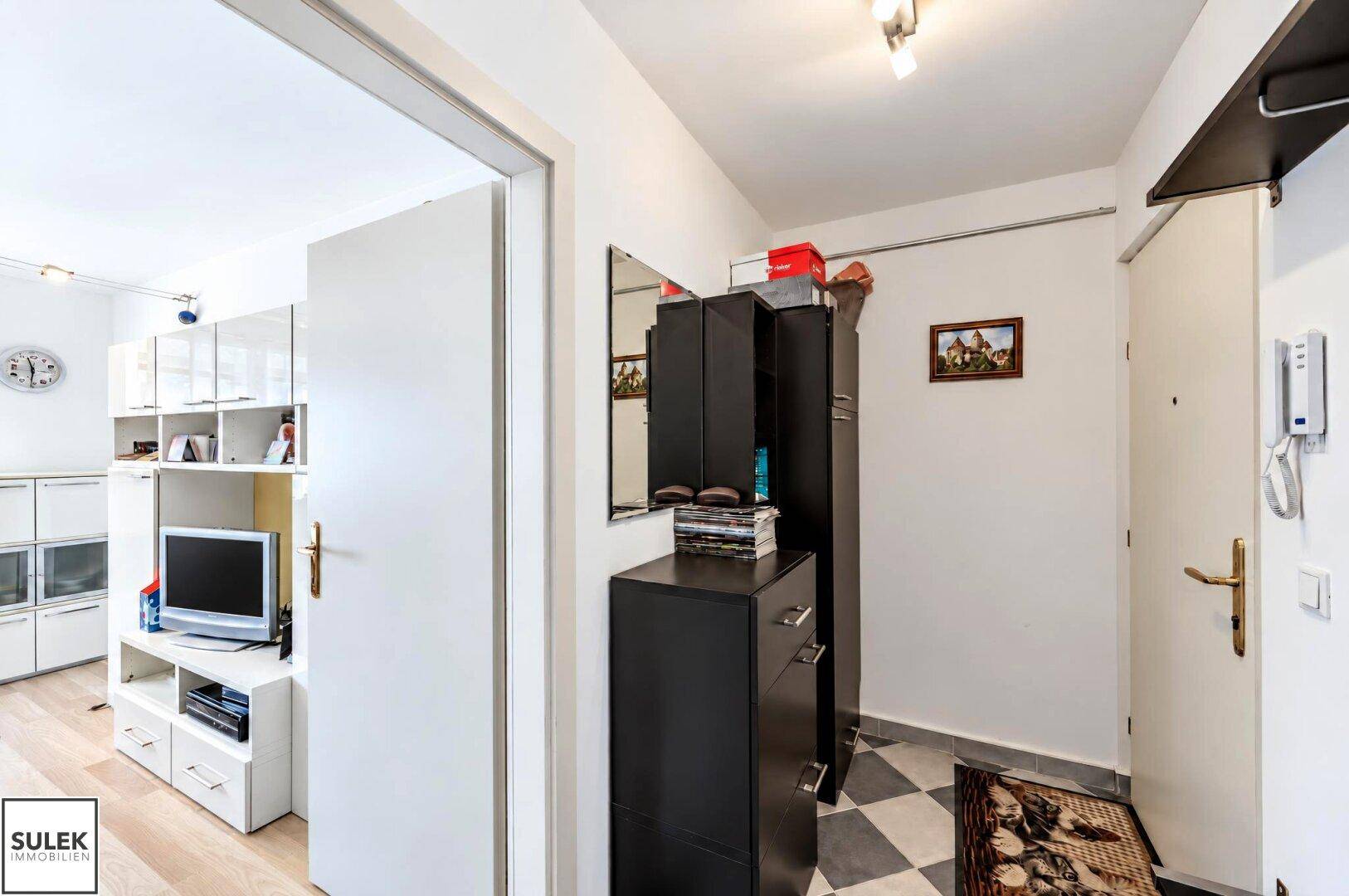 Heller Flur mit Garderobe, Schuhschrank und Zugang zum Wohnbereich.