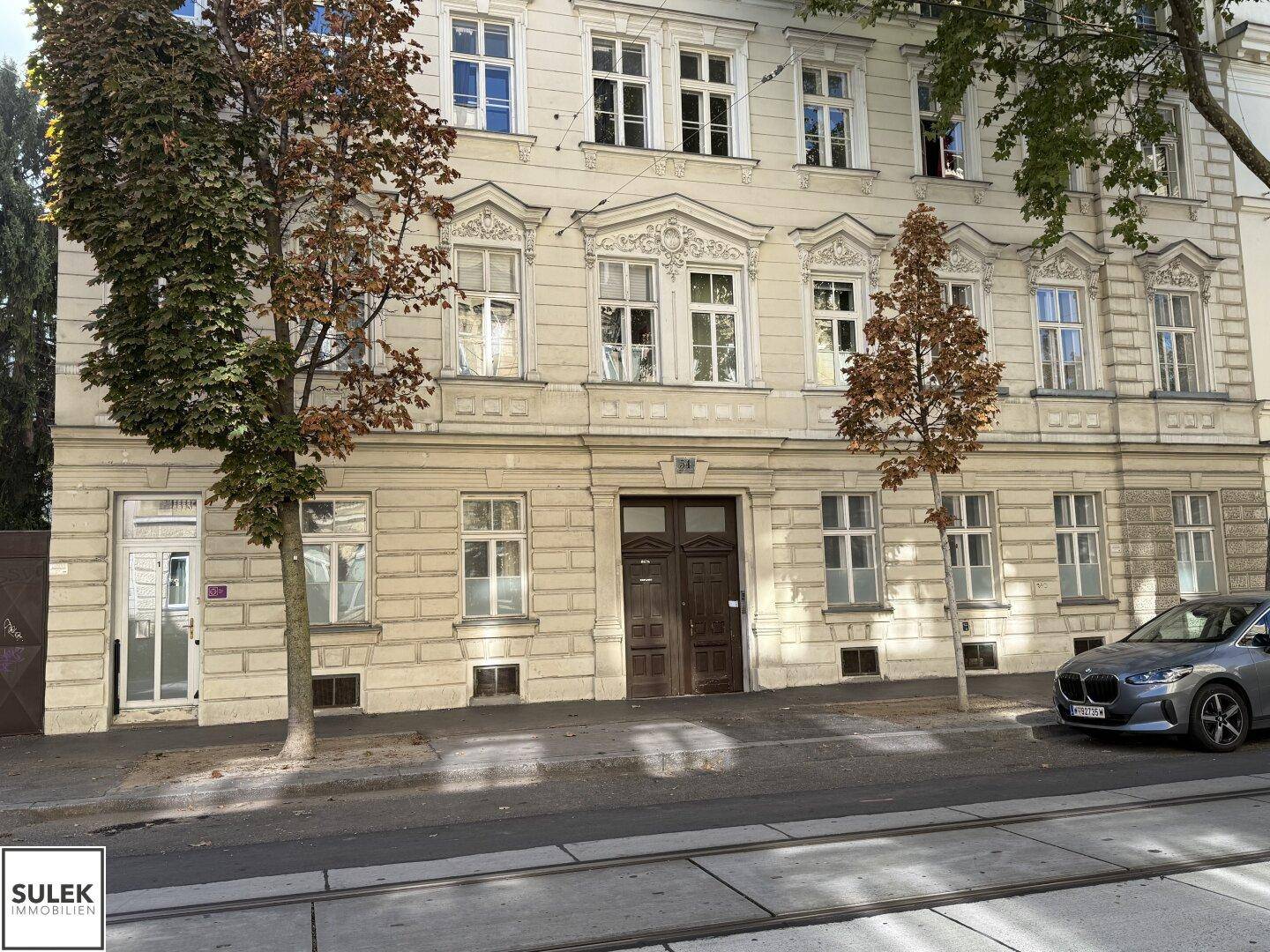 Historisches Gebäude mit reich verzierter Fassade und großen Fenstern, direkt an einer Straße gelegen.