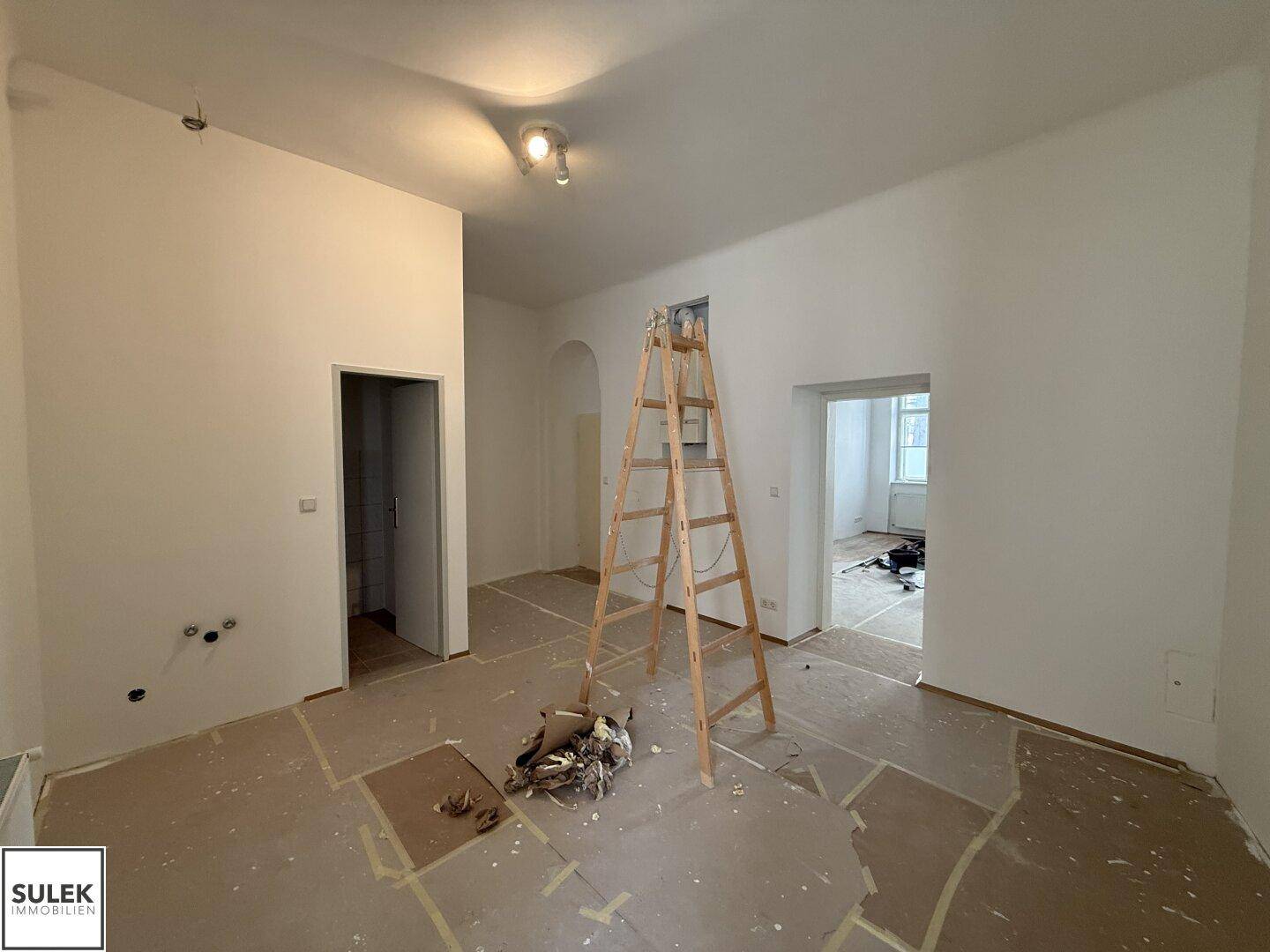Geräumiger Raum in Renovierung mit weißen Wänden und einer Leiter, bereit für die Fertigstellung.