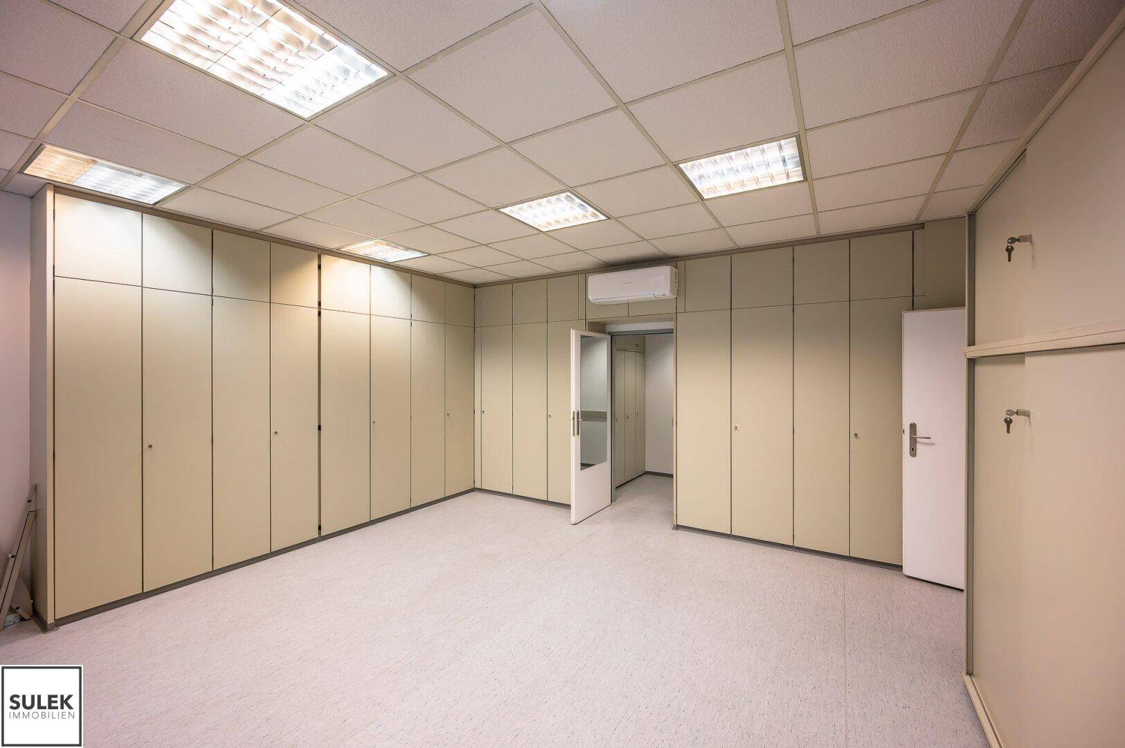 Großes Büro mit vielen Einbauschränken entlang der Wände und hellem Boden.