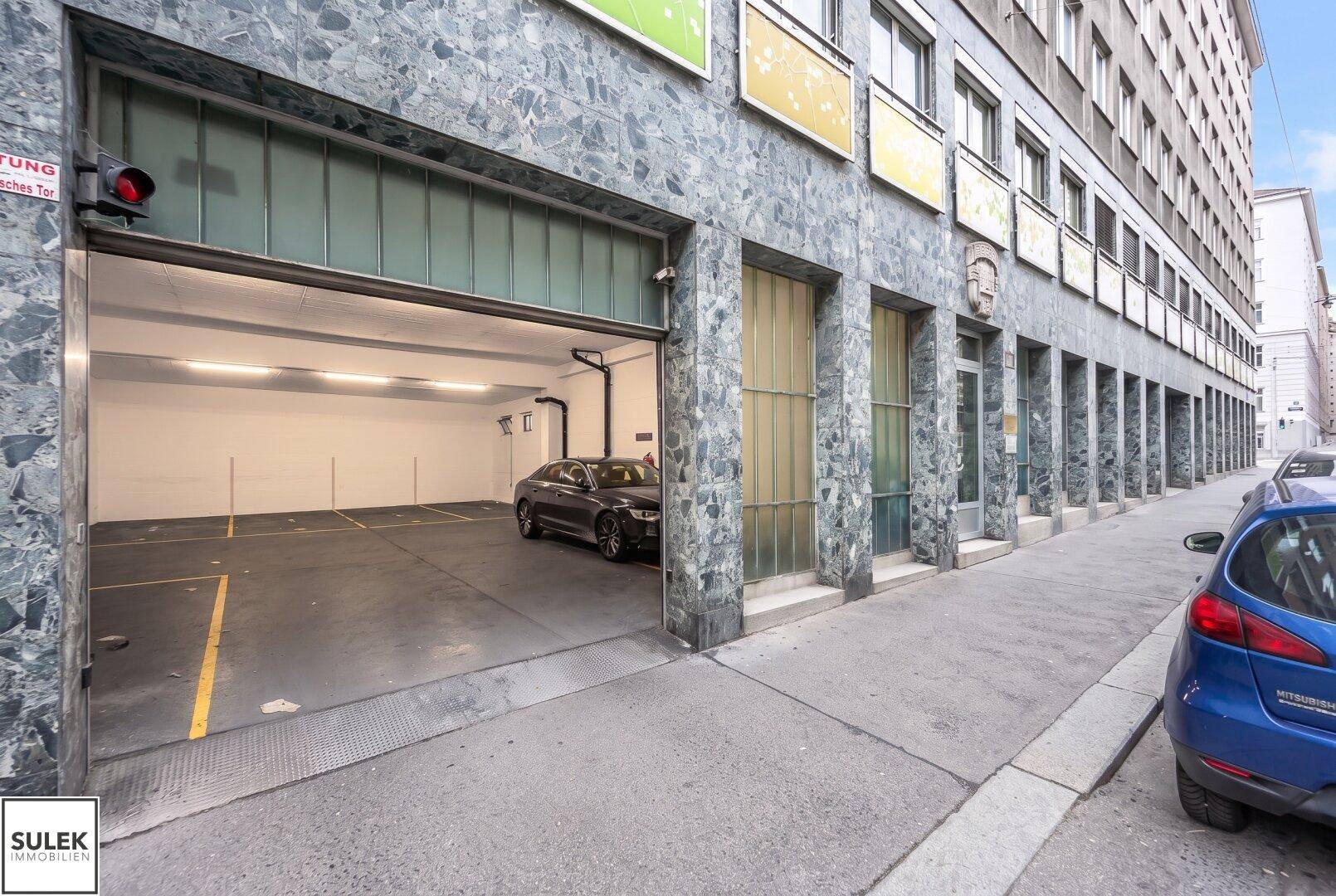 Eingang zu einer Tiefgarage mit einem geparkten Auto und städtischer Umgebung.