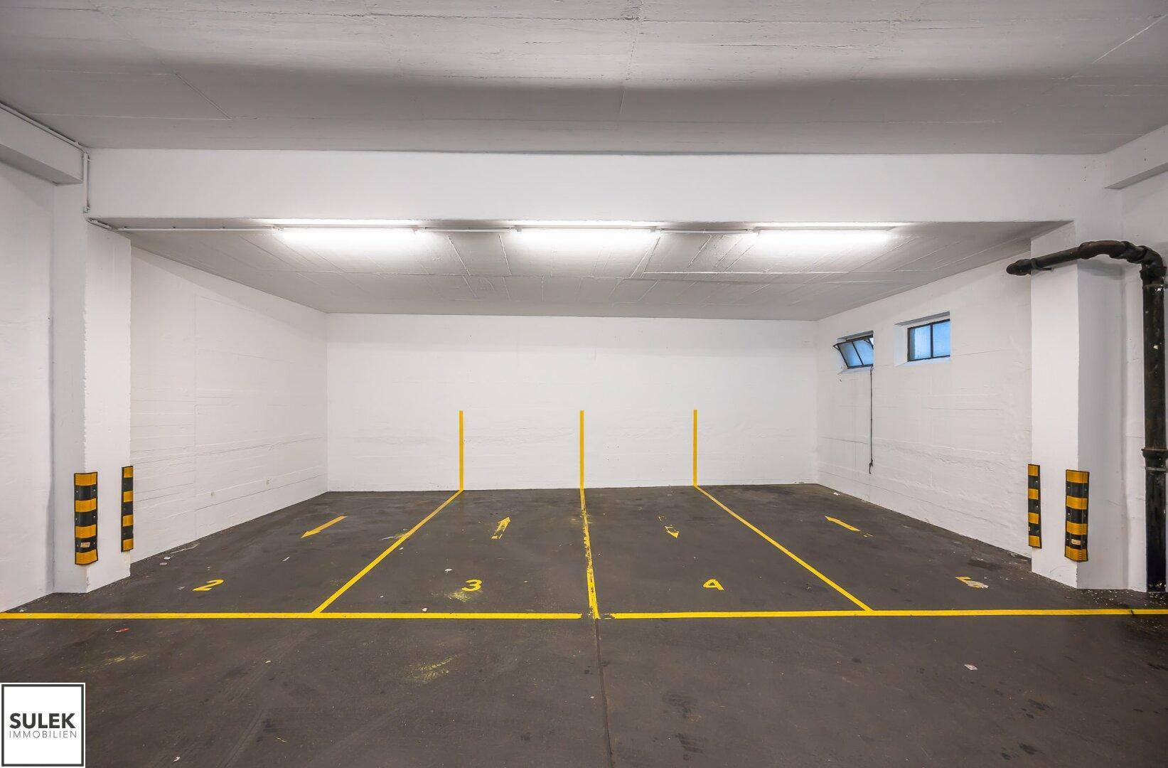 Leere Tiefgarage mit markierten Stellplätzen und guter Beleuchtung.