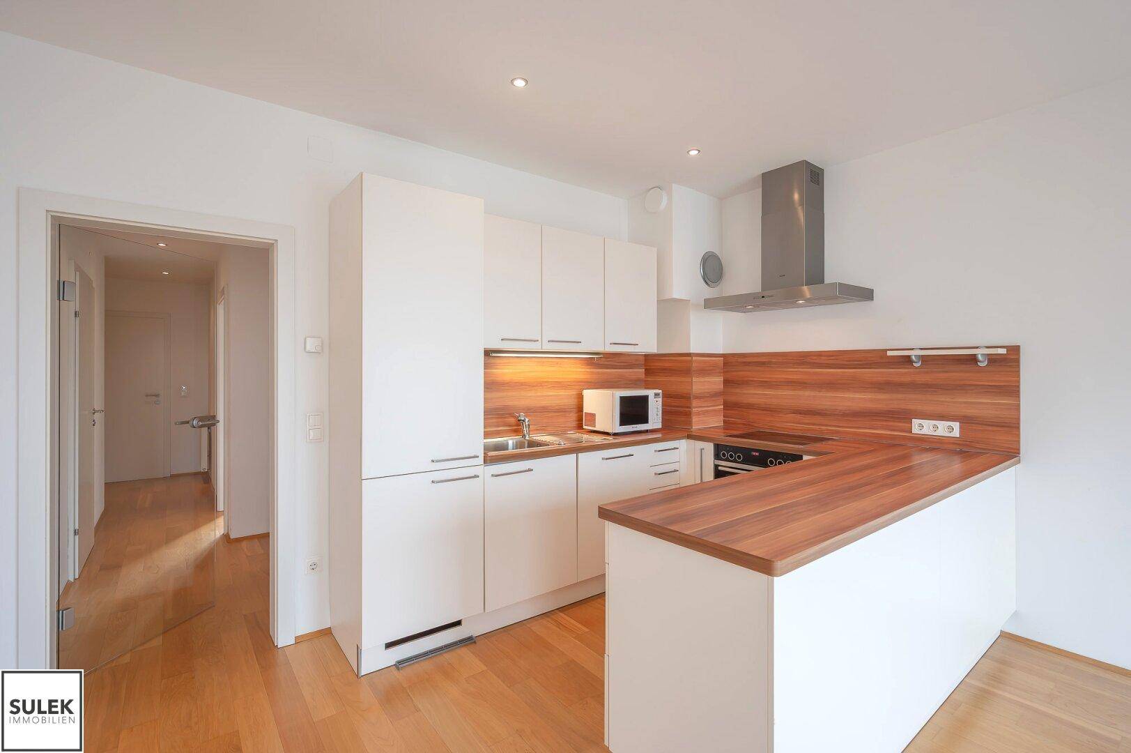 Moderne Einbauküche mit Holz-Arbeitsplatten, integrierten Geräten und viel Stauraum.