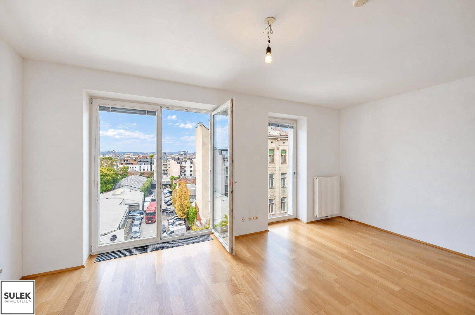 Geräumiges Wohnzimmer mit großen Fenstern, die einen weiten Blick über die Stadt bieten.