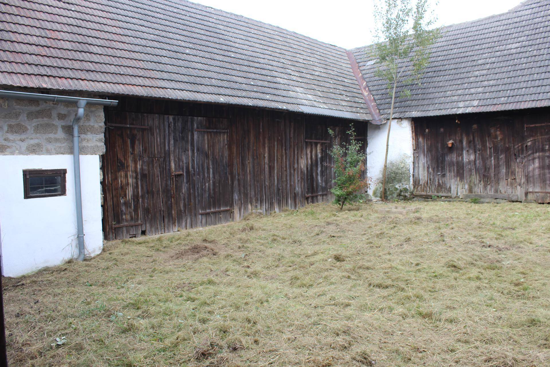 Innenhof mit gemähtem Gras und rustikalen Scheunentoren aus Holz.