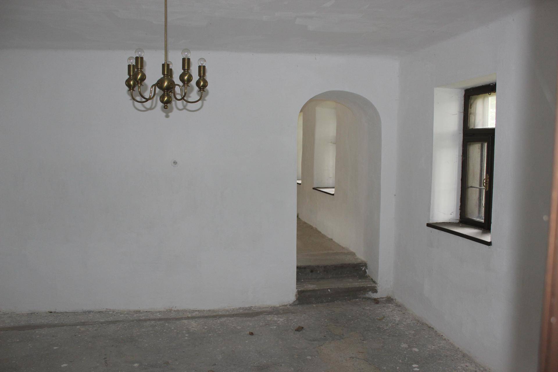 Leerer Raum mit weiß getünchten Wänden, Bogen und einem Fenster.