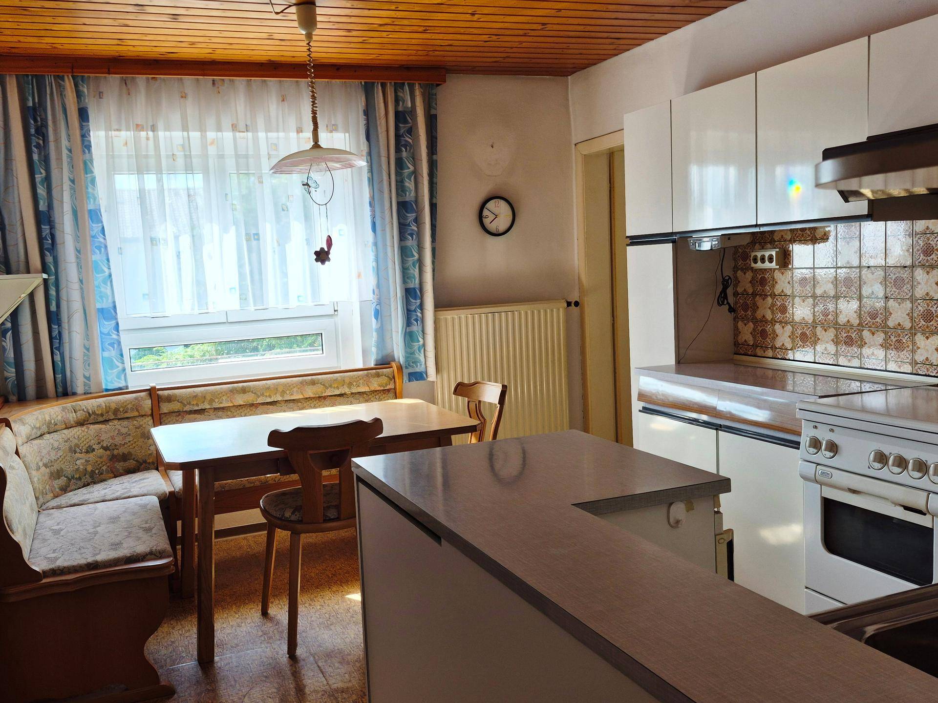 Traditionelle Küche mit Essbereich, Holzdecke, weißen Schränken und Bar-Element.