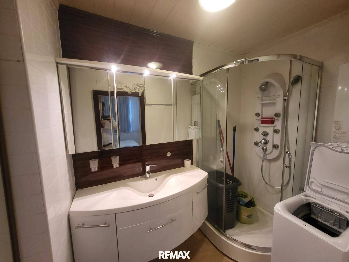Modernes Badezimmer mit Waschbecken, Spiegelschrank und Duschkabine.