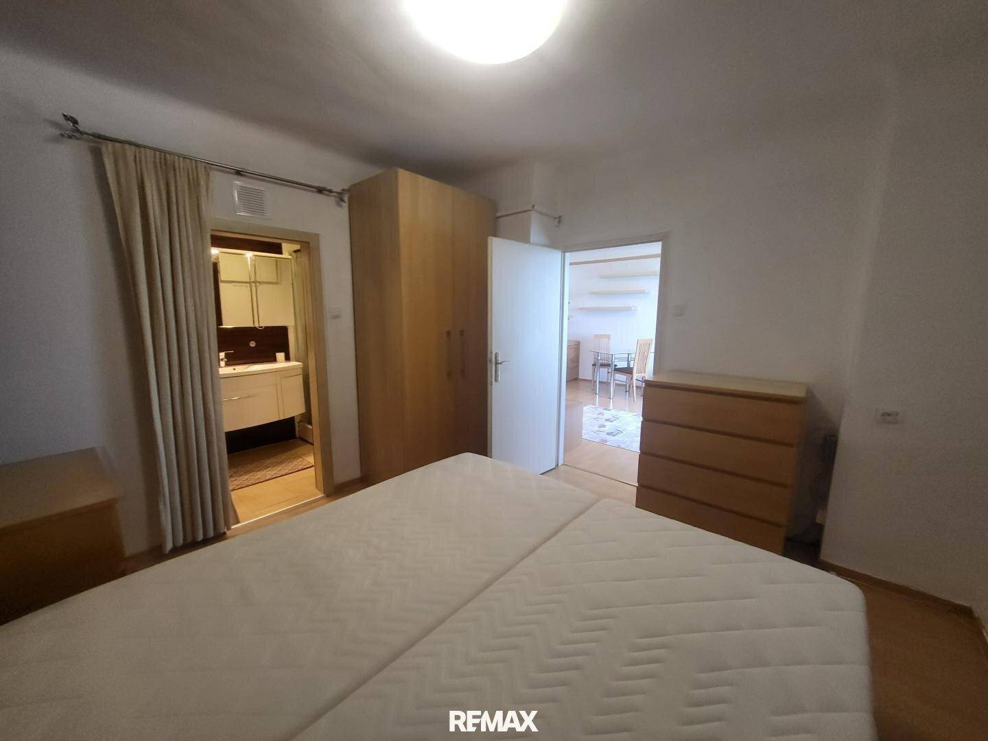 Schlafzimmer mit Doppelbett und Kleiderschrank, mit Blick in den Wohnbereich.