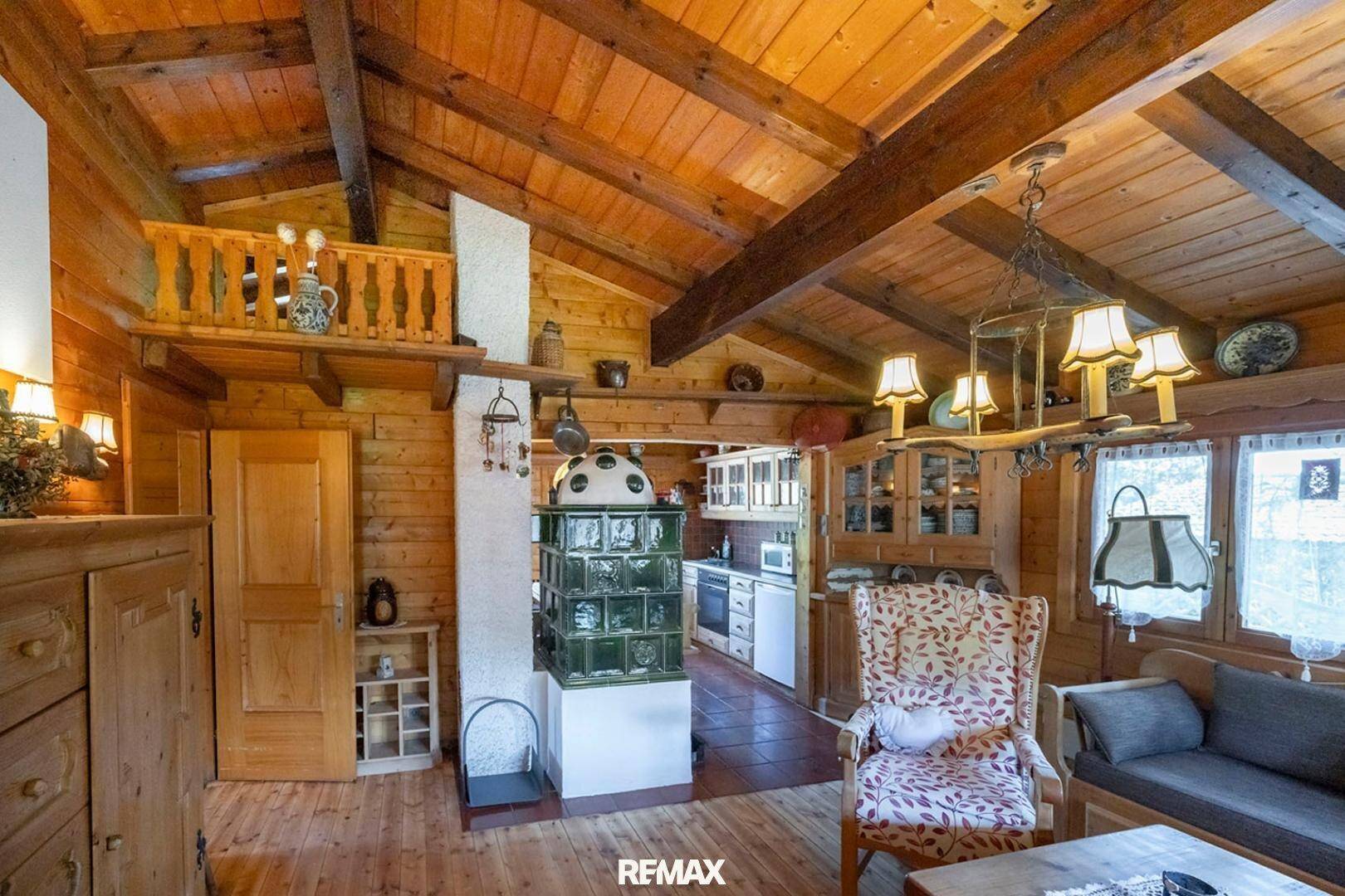 Geräumiger Wohnbereich im Chalet-Stil mit Kachelofen, Holzbalken und offener Galerie.