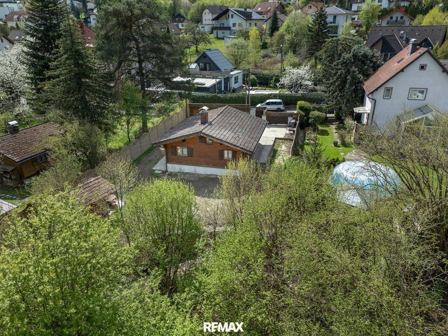 Überblick aus der Vogelperspektive auf das Holzhaus und die umliegende Siedlung.