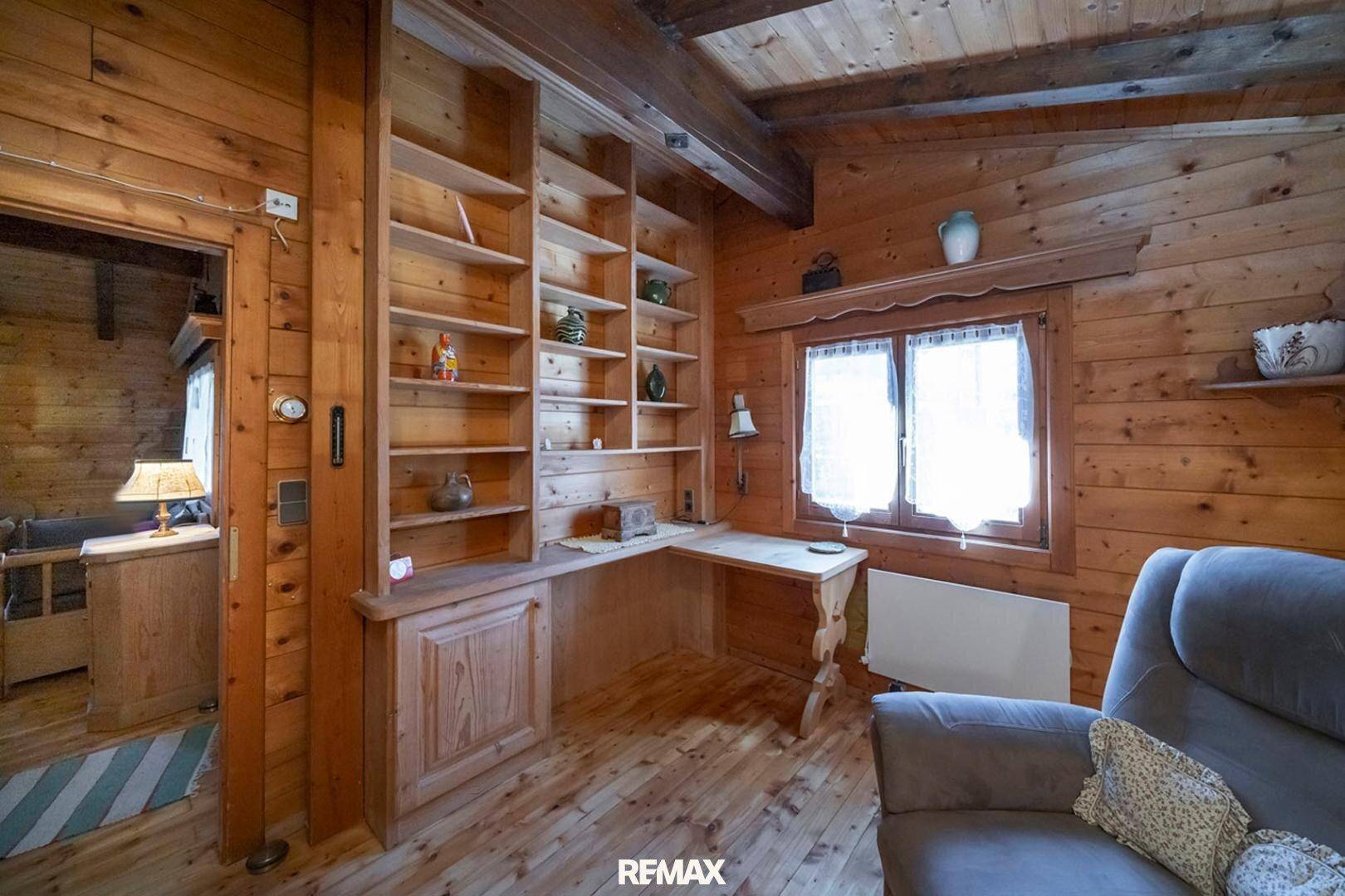Arbeitszimmer mit eingebautem Bücherregal, Holzvertäfelung und Blick ins Grüne.