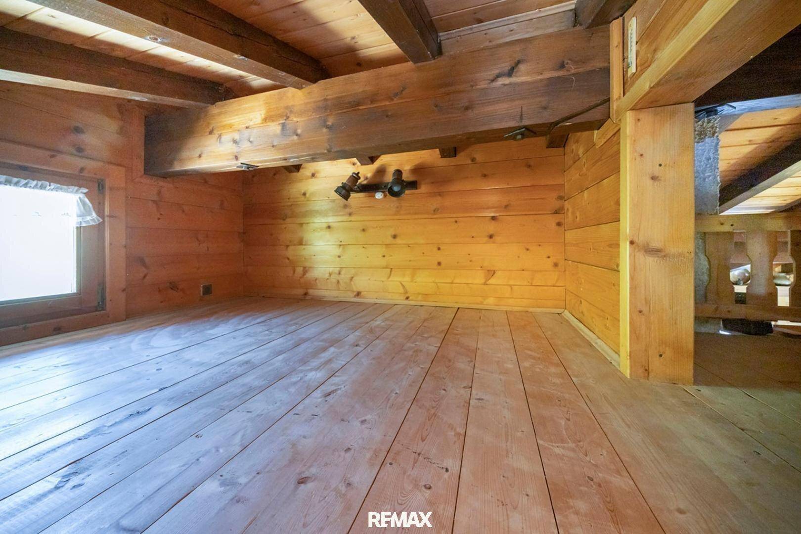 Leerer Raum mit Holzboden und sichtbaren Holzbalken, bereit zur individuellen Gestaltung.