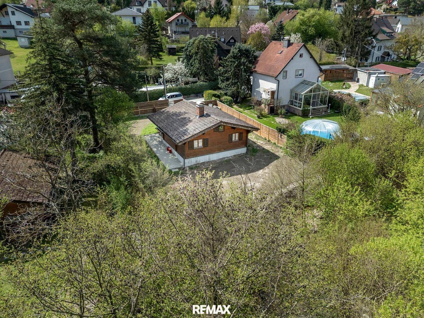Luftaufnahme des Holzhauses in einer grünen Wohngegend mit weiteren Häusern.