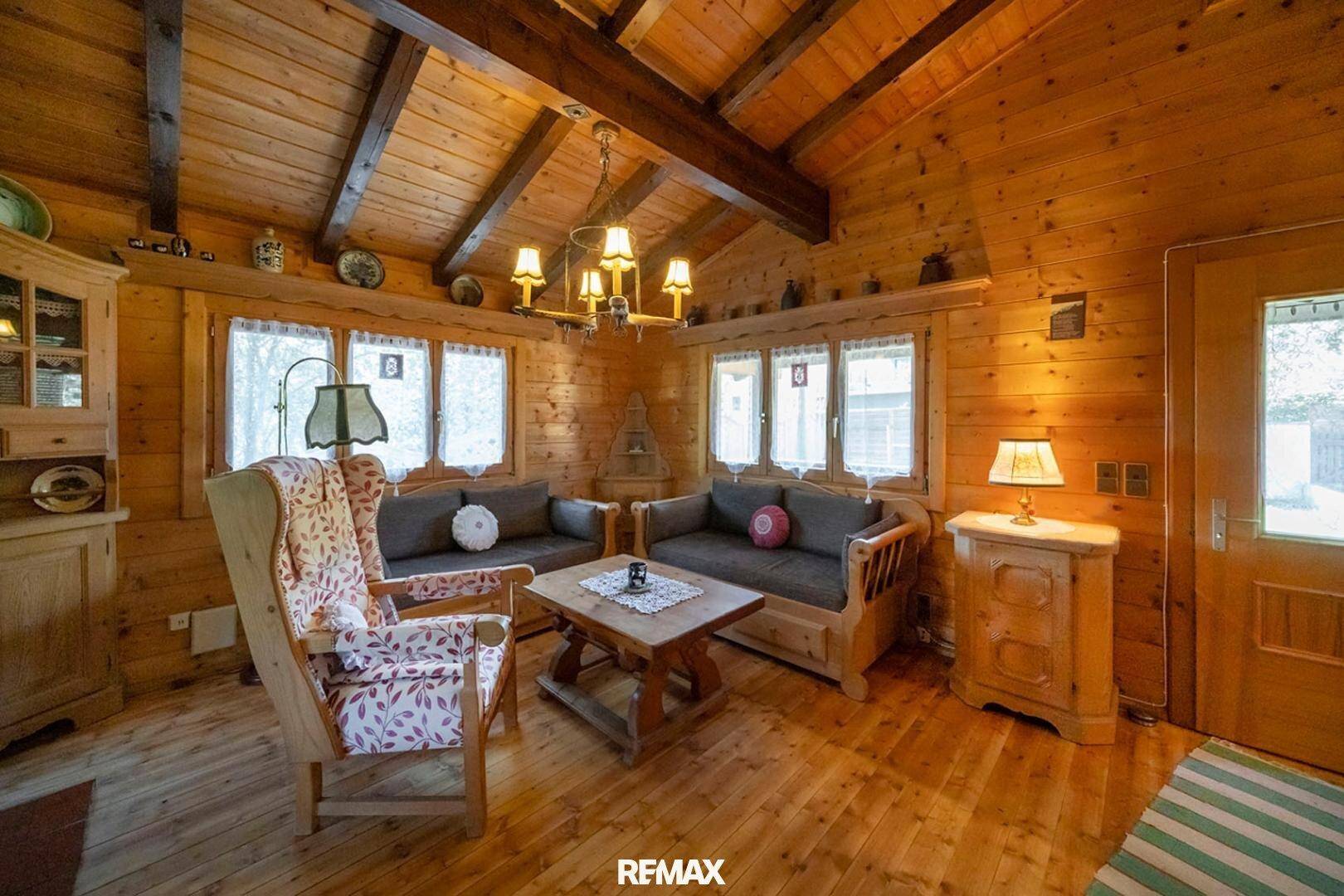 Gemütliches Wohnzimmer im Chalet-Stil mit Holzbalken, Holzvertäfelung und traditionellen Möbeln.