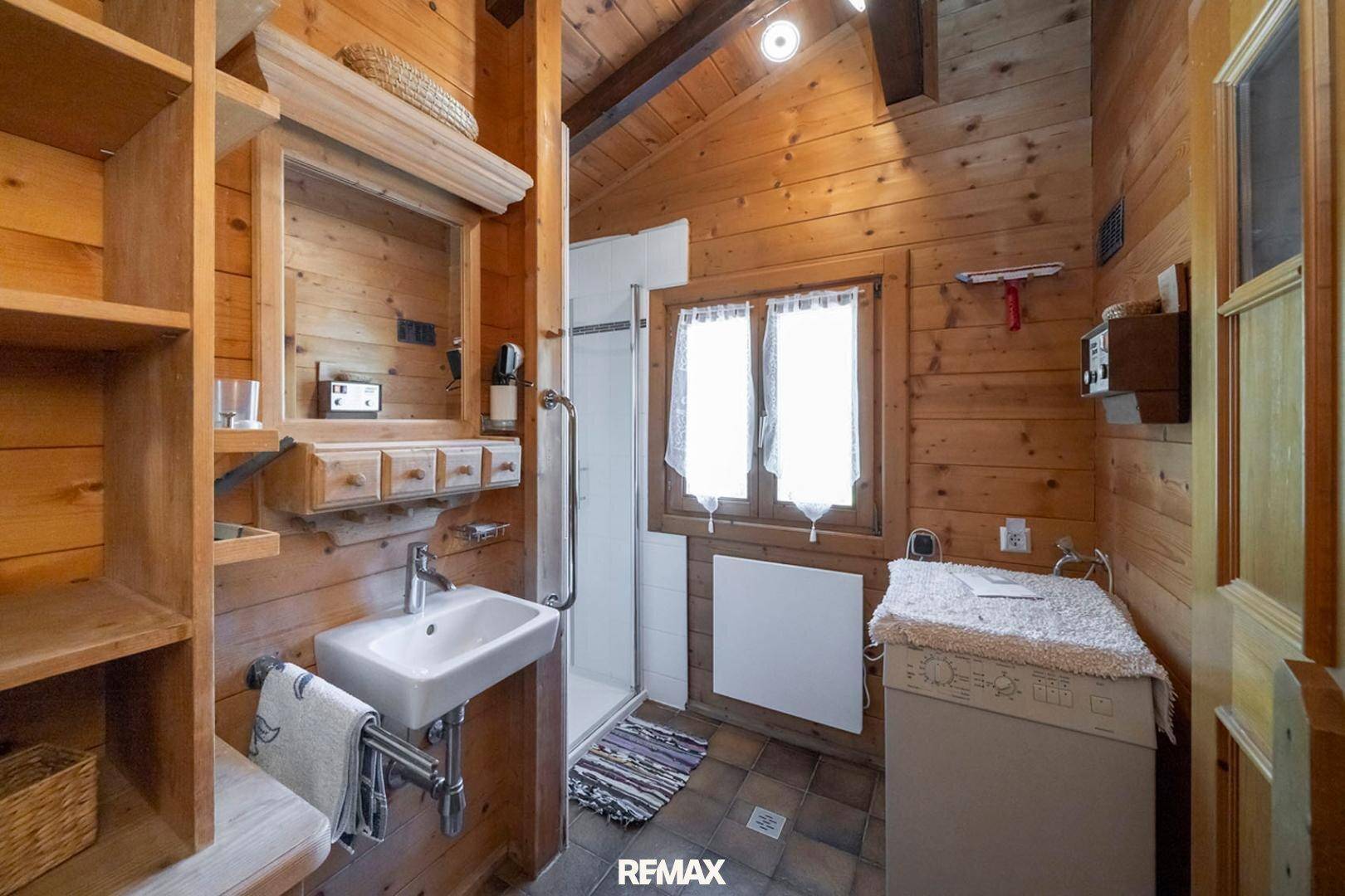 Rustikales Badezimmer mit Holzvertäfelung, Dusche und Waschmaschine.