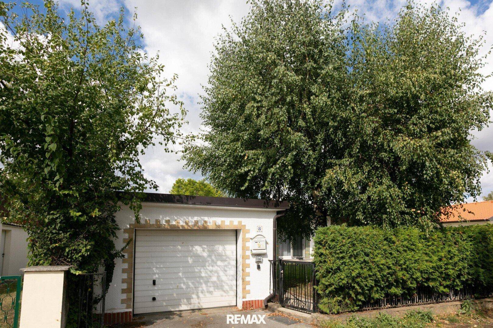 Vorderansicht des Hauses mit Garage, Hecke und Zufahrt.