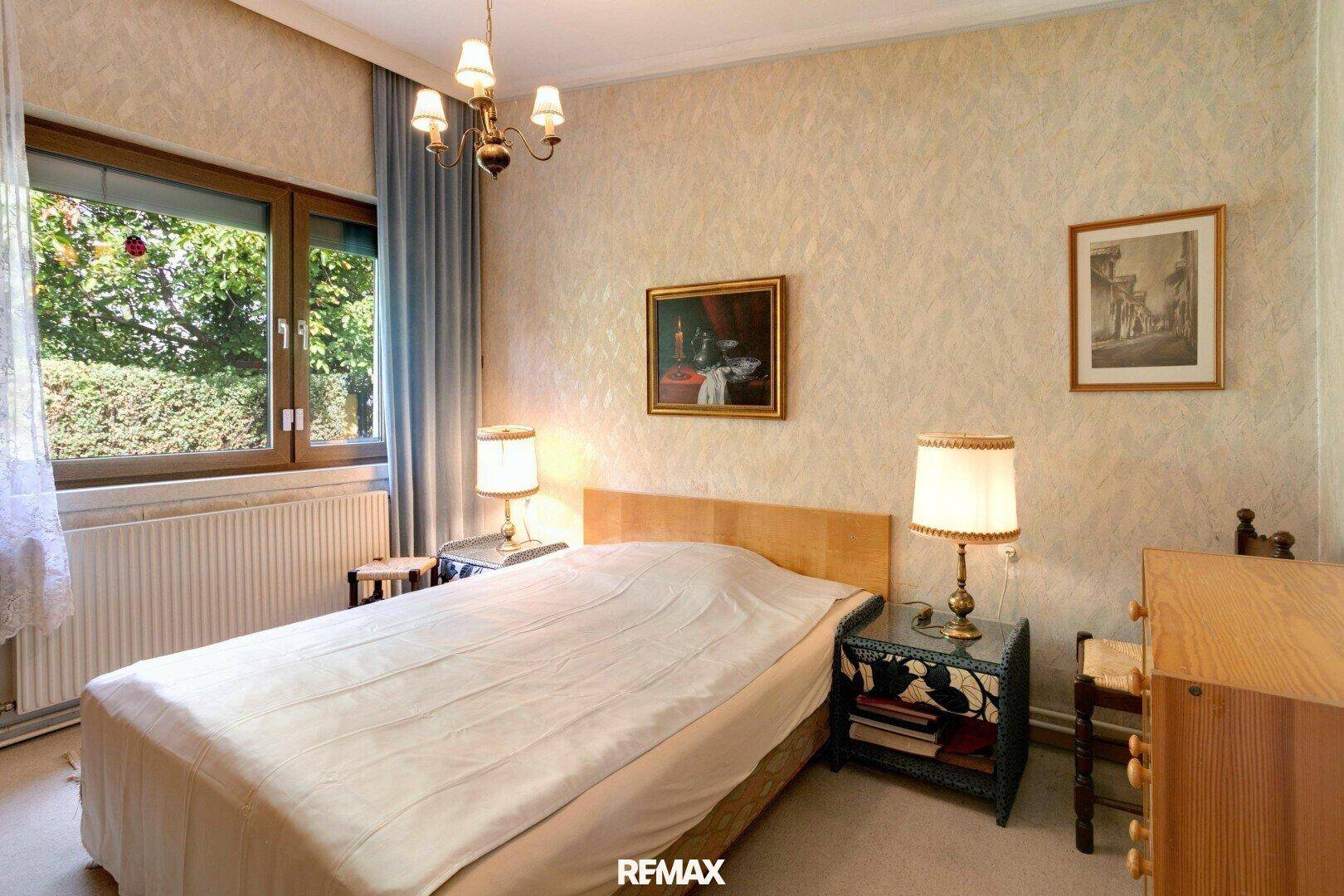 Schlafzimmer mit Einzelbett, gemusterter Tapete und traditionellen Nachttischen.