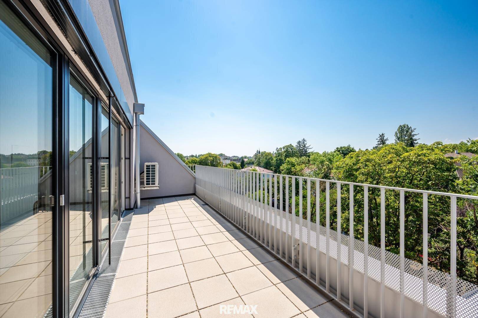 Weitläufige Dachterrasse mit hellen Fliesen und Panoramablick, ideal für Entspannung im Freien.