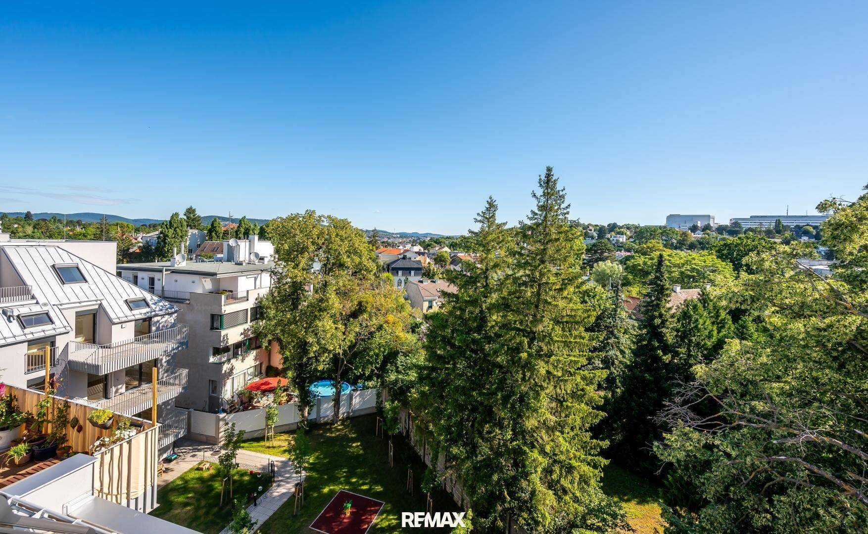 Blick von oben auf einen gepflegten Gemeinschaftsgarten mit Spielplatz und viel Grünfläche.