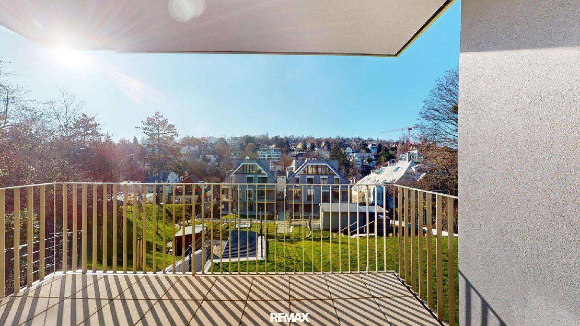 Sonniger Balkon mit Fliesenboden und weitem Blick über die grüne Umgebung und die Stadt.