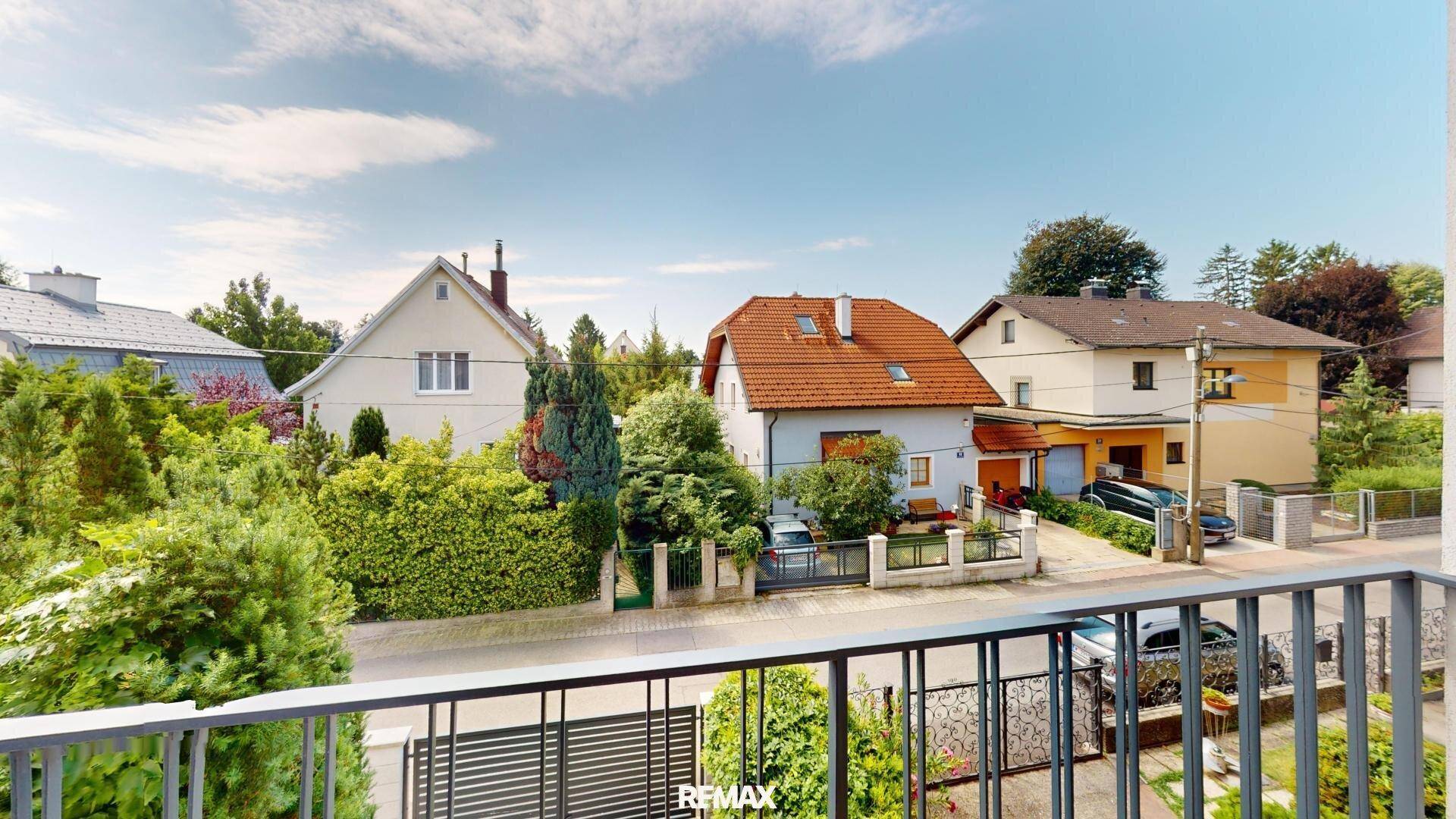 Blick von einem Balkon auf die ruhige Wohnstraße mit umliegenden Einfamilienhäusern.
