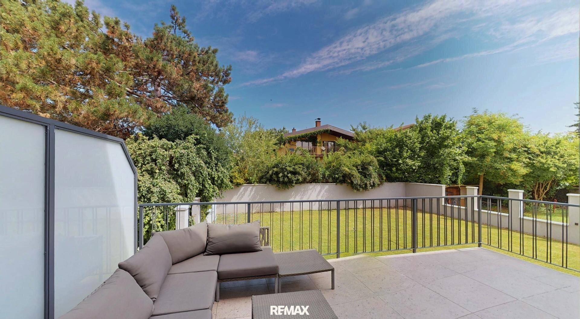 Große Sonnenterrasse mit bequemen Lounge-Möbeln und Blick auf den gepflegten Garten.