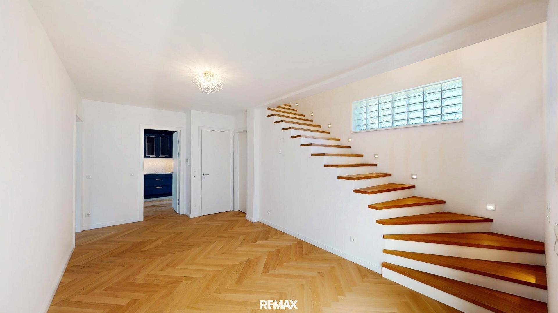 Heller Flur mit elegantem Fischgrätparkett und offener Treppe zu den oberen Etagen.