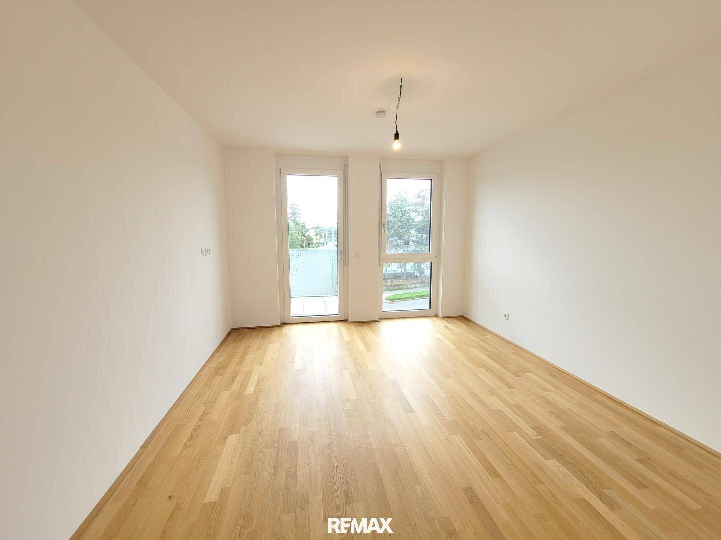 Helles Schlafzimmer mit Parkettboden und direktem Zugang zum Balkon.