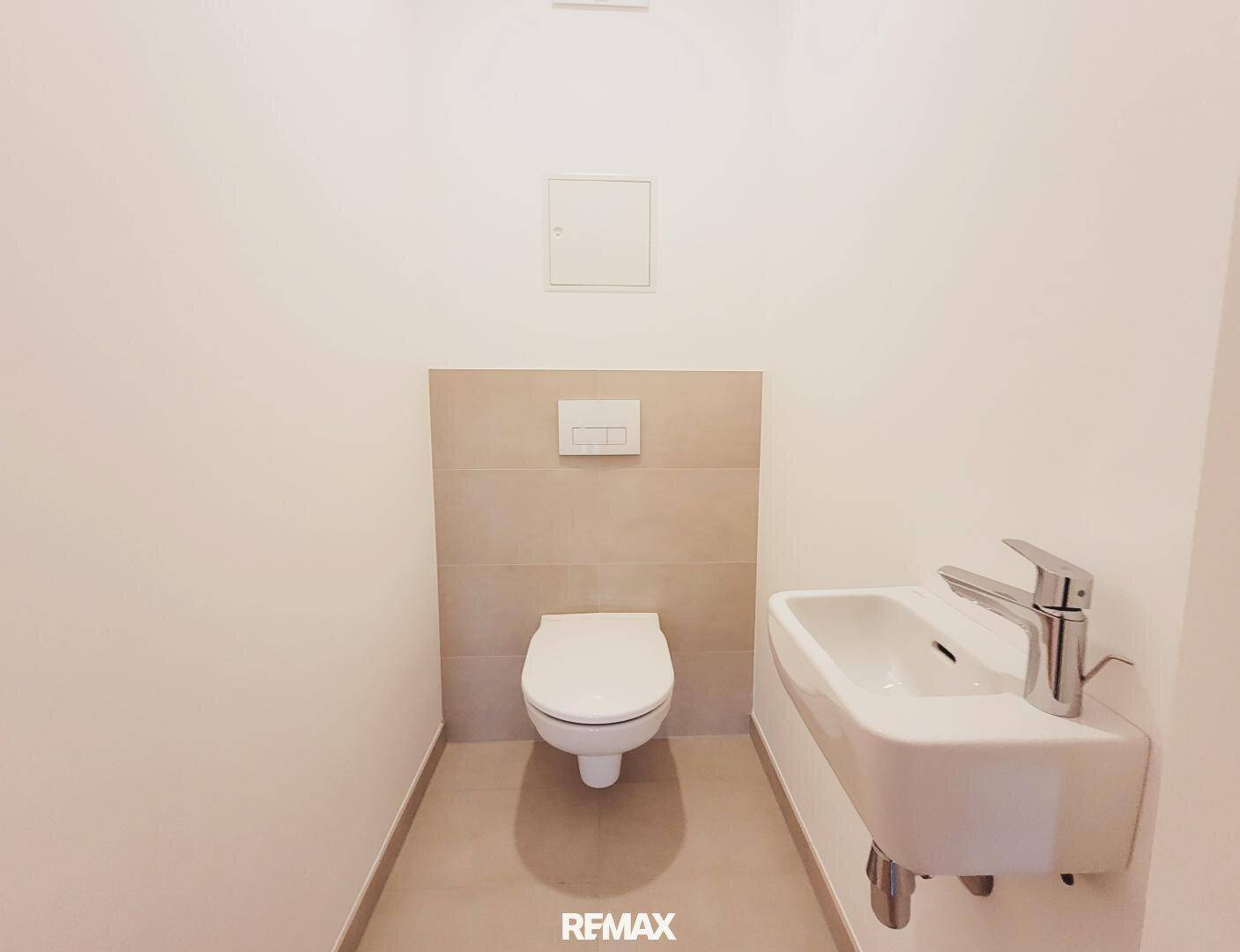 Modernes Gäste-WC mit wandhängendem WC und kleinem Waschbecken.
