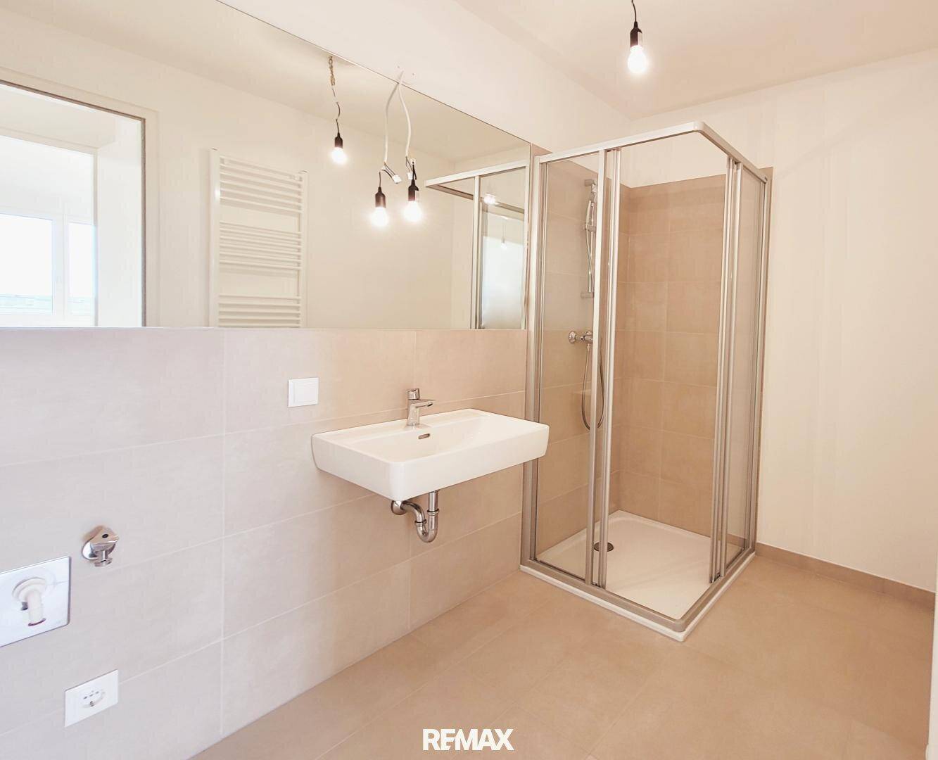Modernes Badezimmer mit Duschkabine, Waschbecken und beheiztem Handtuchhalter.