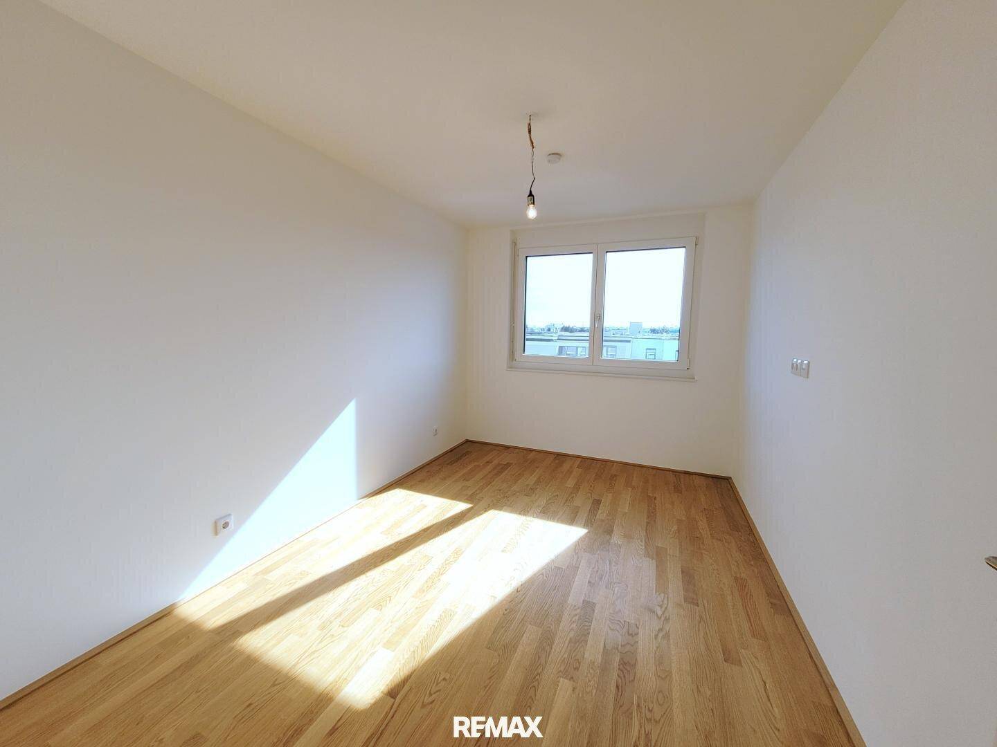Weiteres helles Zimmer mit Parkettboden und Fenster, ideal als Schlaf- oder Arbeitszimmer.
