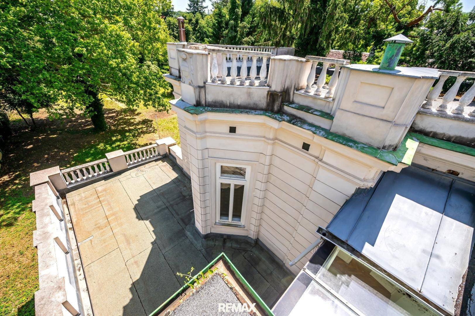 Historisches Gebäude mit Dachterrasse, klassischer Balustrade und Blick auf die Umgebung.