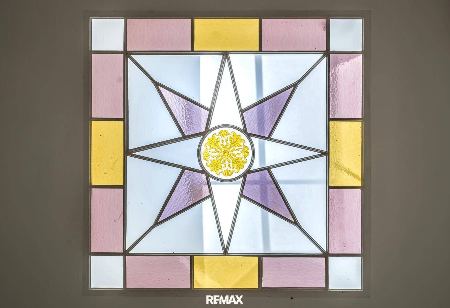 Dekoratives Buntglasfenster mit geometrischem Muster in Pastellfarben.