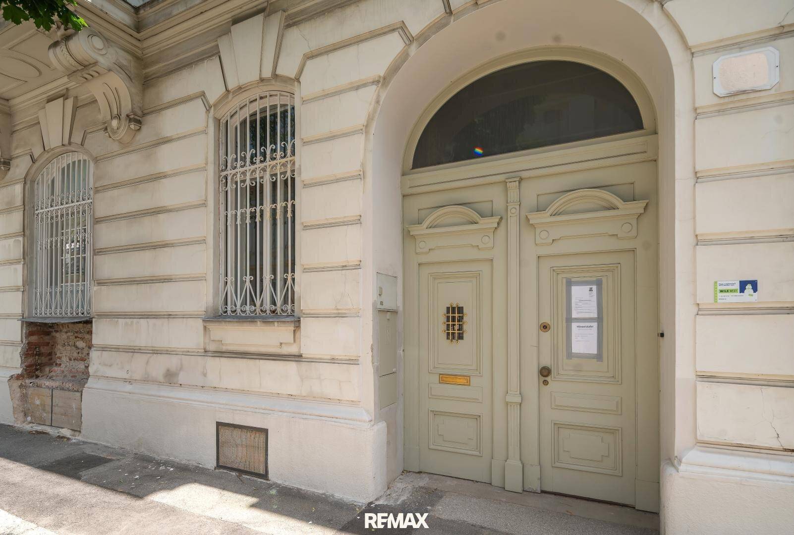 Historische Fassade mit großer Holztür und dekorativen Fenstergittern.