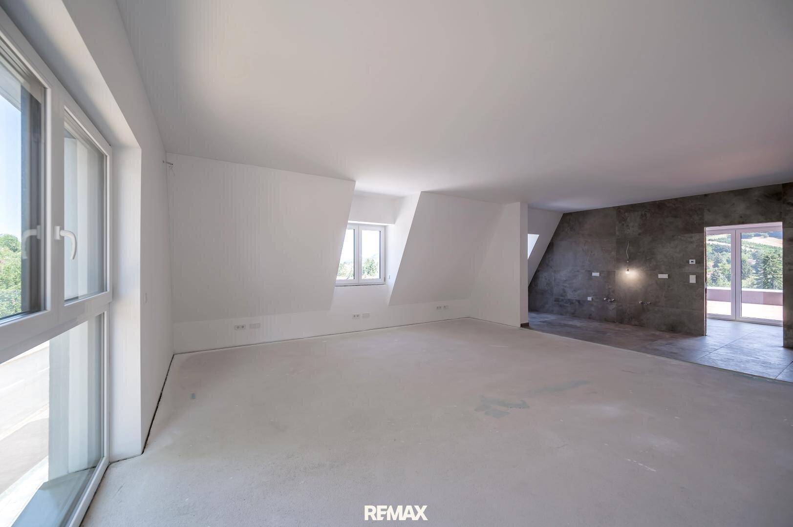 Geräumiger Dachgeschossraum mit schrägen Wänden und großen Fenstern, ideal für ein Schlafzimmer.