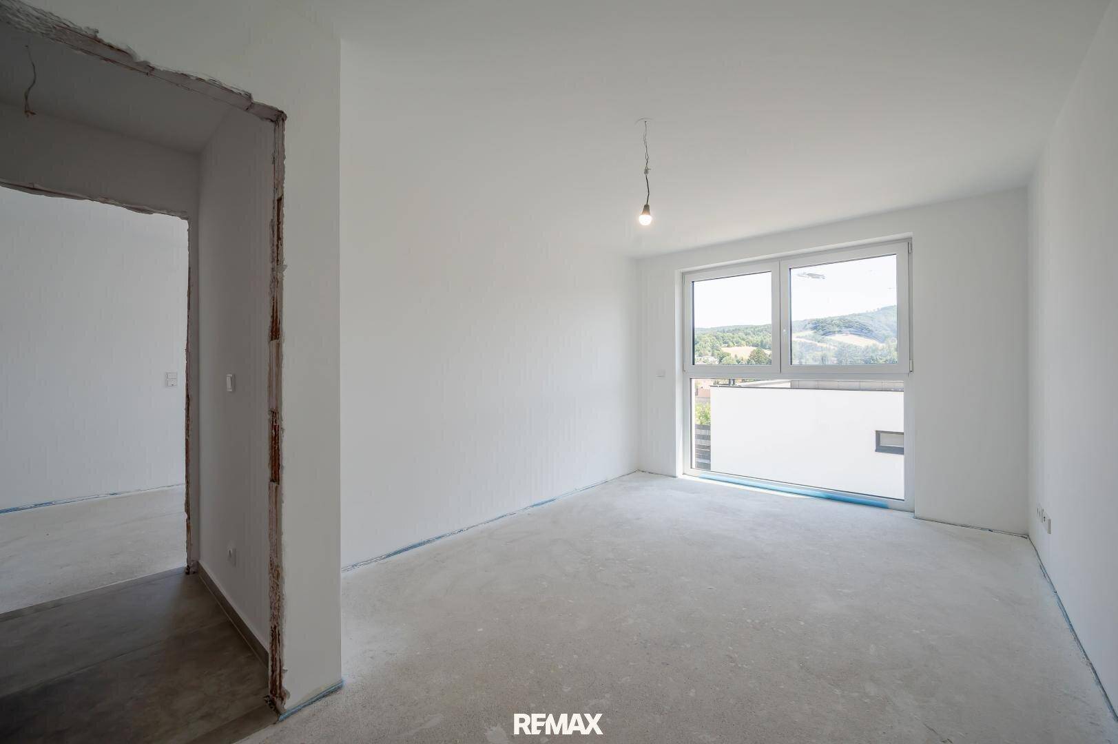 Helles Zimmer mit großem Fenster und Blick ins Grüne, bereit für individuelle Gestaltung.