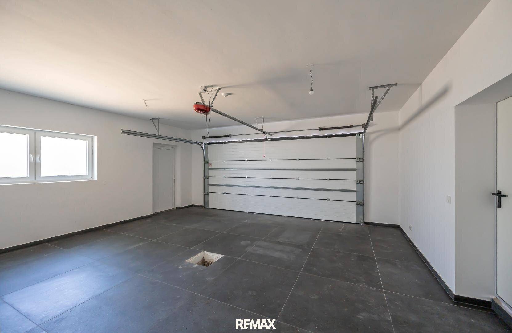 Geräumige Doppelgarage mit Fliesenboden und großem Garagentor, bereit zur Nutzung.