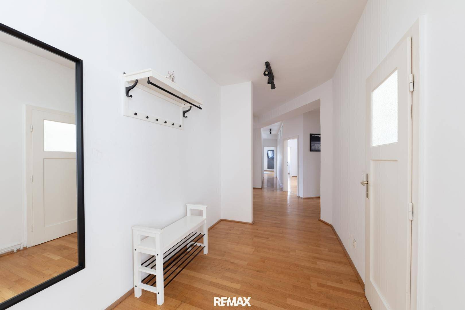 Heller Eingangsbereich mit Holzboden, Garderobe und Spiegel, der zu den Wohnräumen führt.
