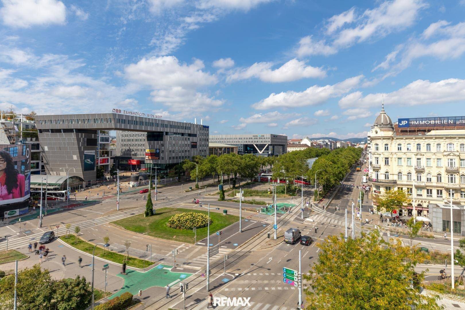 Weitläufiger Panoramablick über eine belebte Stadtkreuzung mit modernen Gebäuden und Grünflächen.