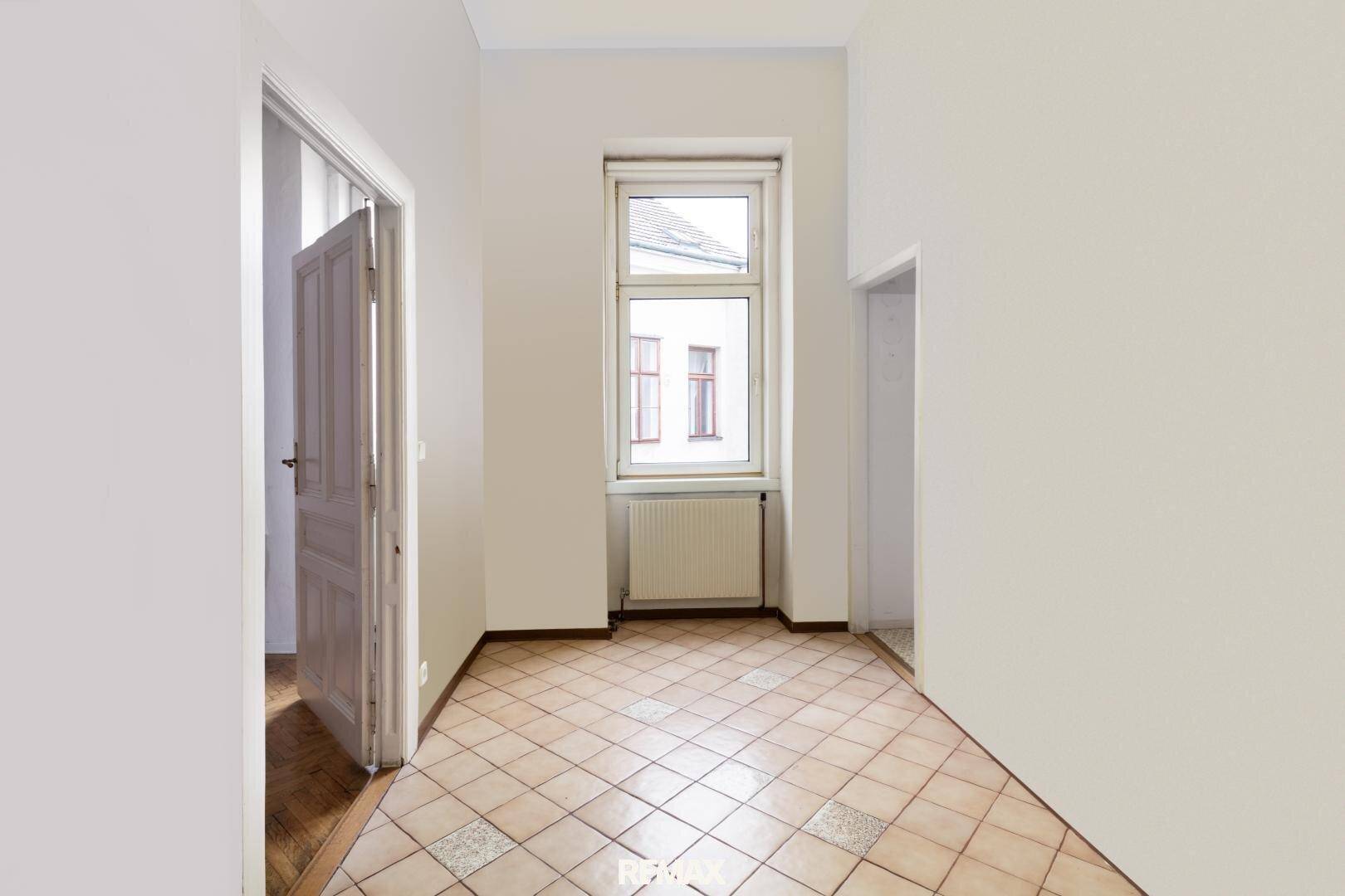 Flur mit gemusterten Fliesen und einem hohen Fenster, das den Raum erhellt.