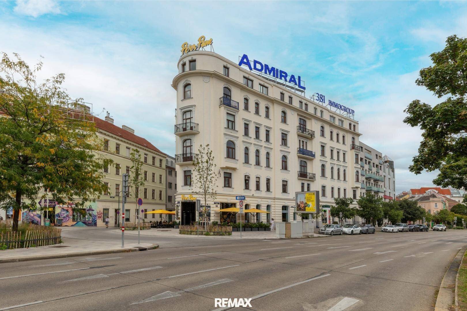 Großes Eckgebäude mit Geschäften und Wohnungen an einer belebten Stadtstraße.