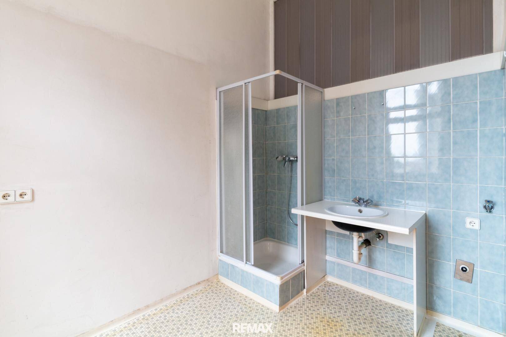 Badezimmer mit Duschkabine und Waschtisch, ausgestattet mit blauen Wandfliesen.