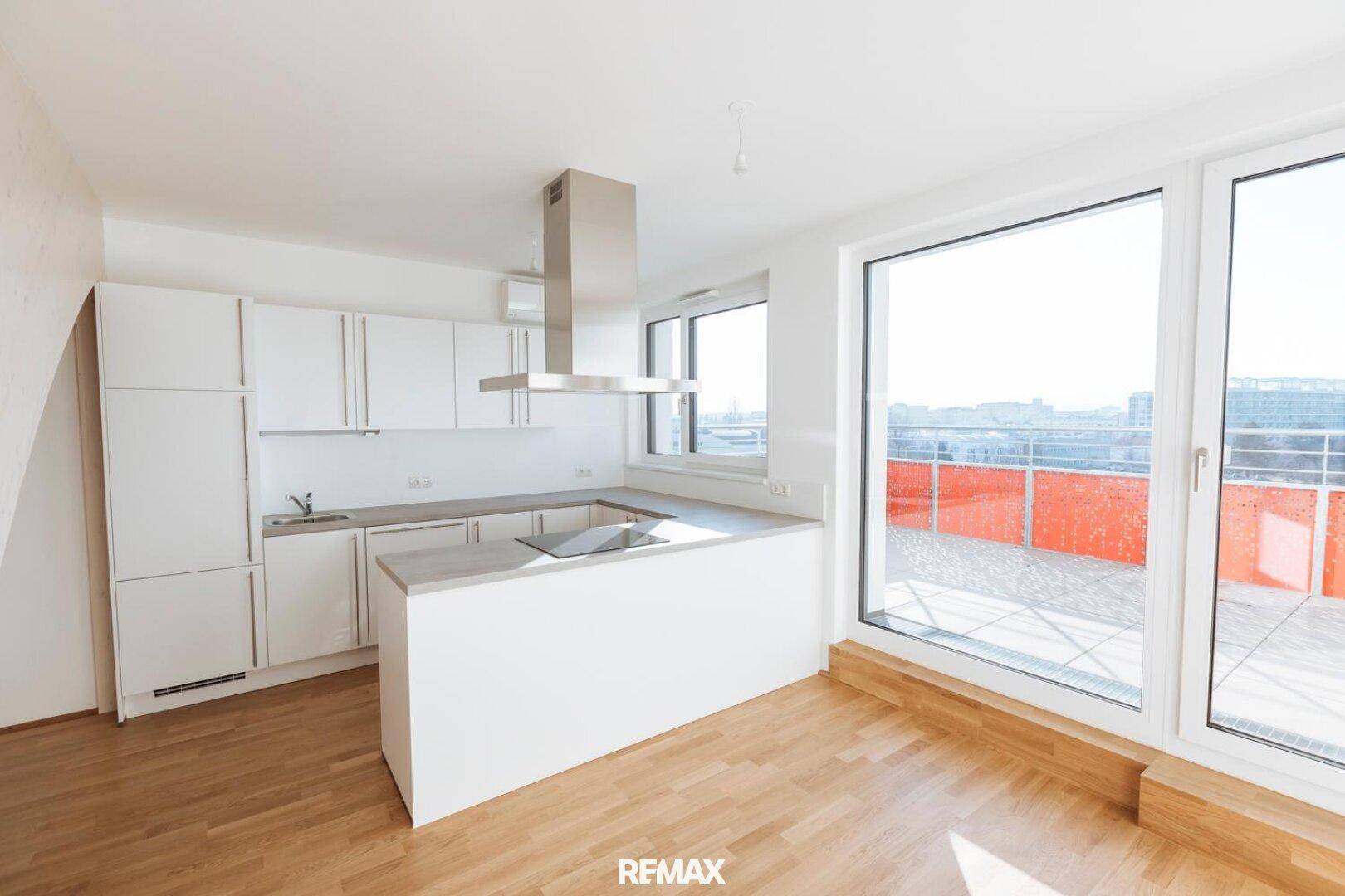 Helle, moderne Küche mit weißen Schränken, Holzboden und Zugang zur Terrasse.