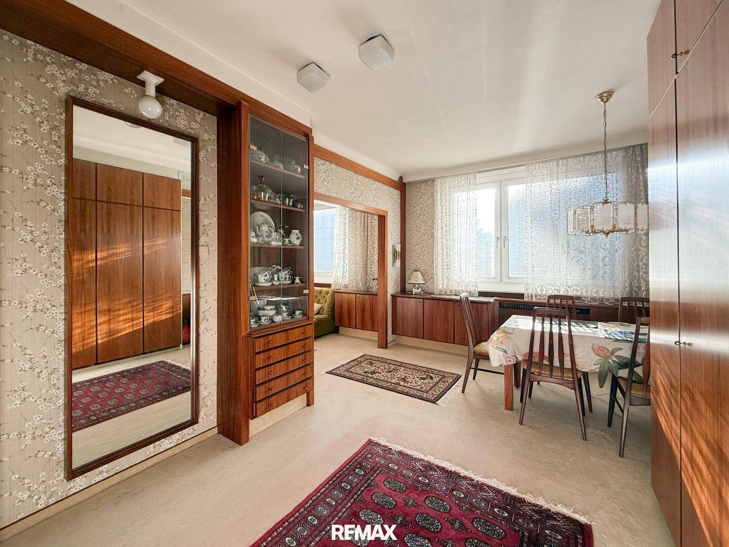 Esszimmer mit Holztisch und Stühlen, angrenzend an einen Wohnbereich im Vintage-Stil.