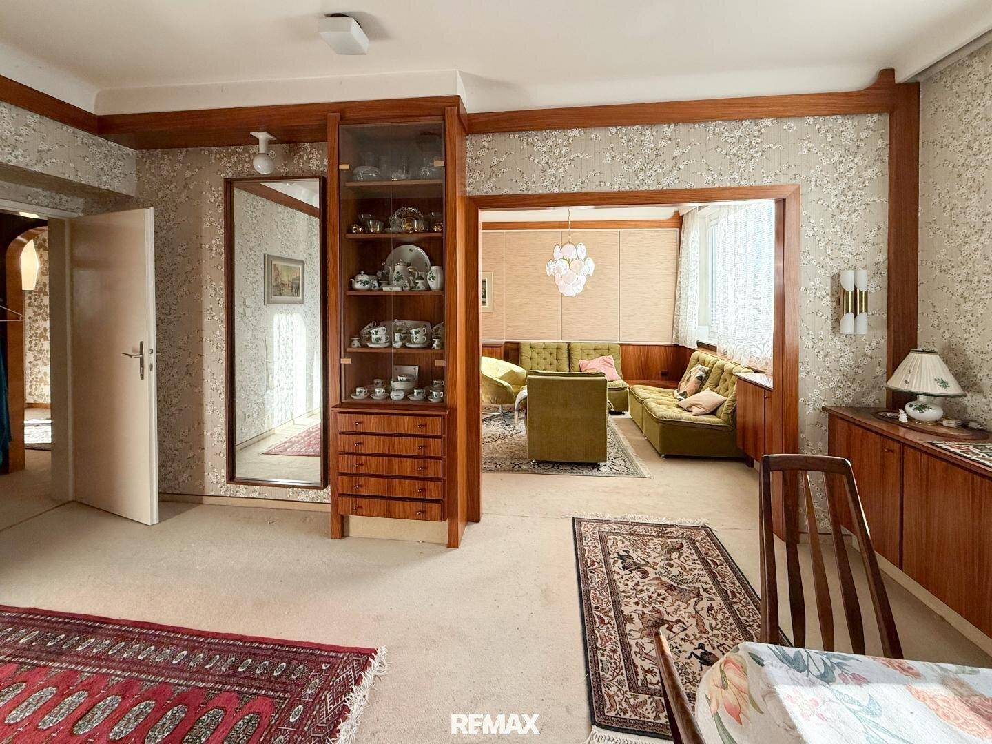 Esszimmer mit Holztisch und Stühlen, Blick in ein angrenzendes Wohnzimmer.