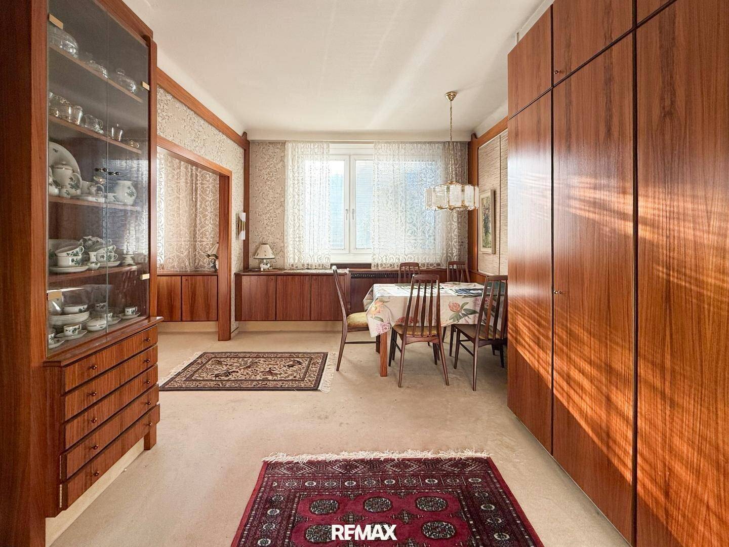 Esszimmer im Vintage-Stil mit Holztisch, Stühlen und Teppichen, angrenzend an den Wohnbereich.